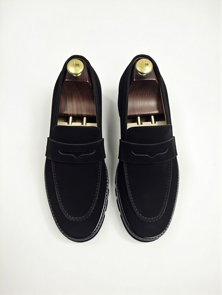 Pair of black loafers with gold buttons on a white background