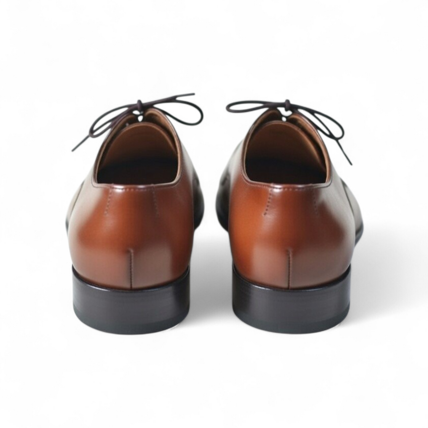 Pair of brown leather shoes with black soles on a white background