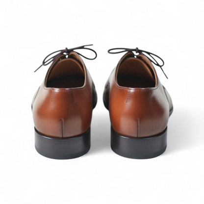Pair of brown leather shoes with black soles on a white background