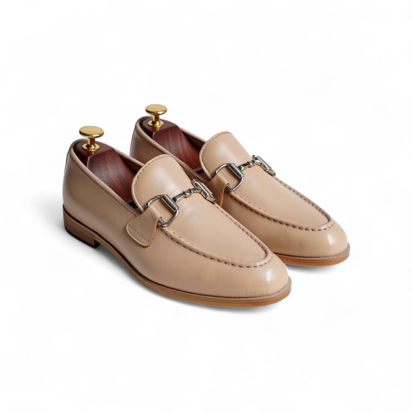 Pair of beige loafers with metallic buckles on a white background