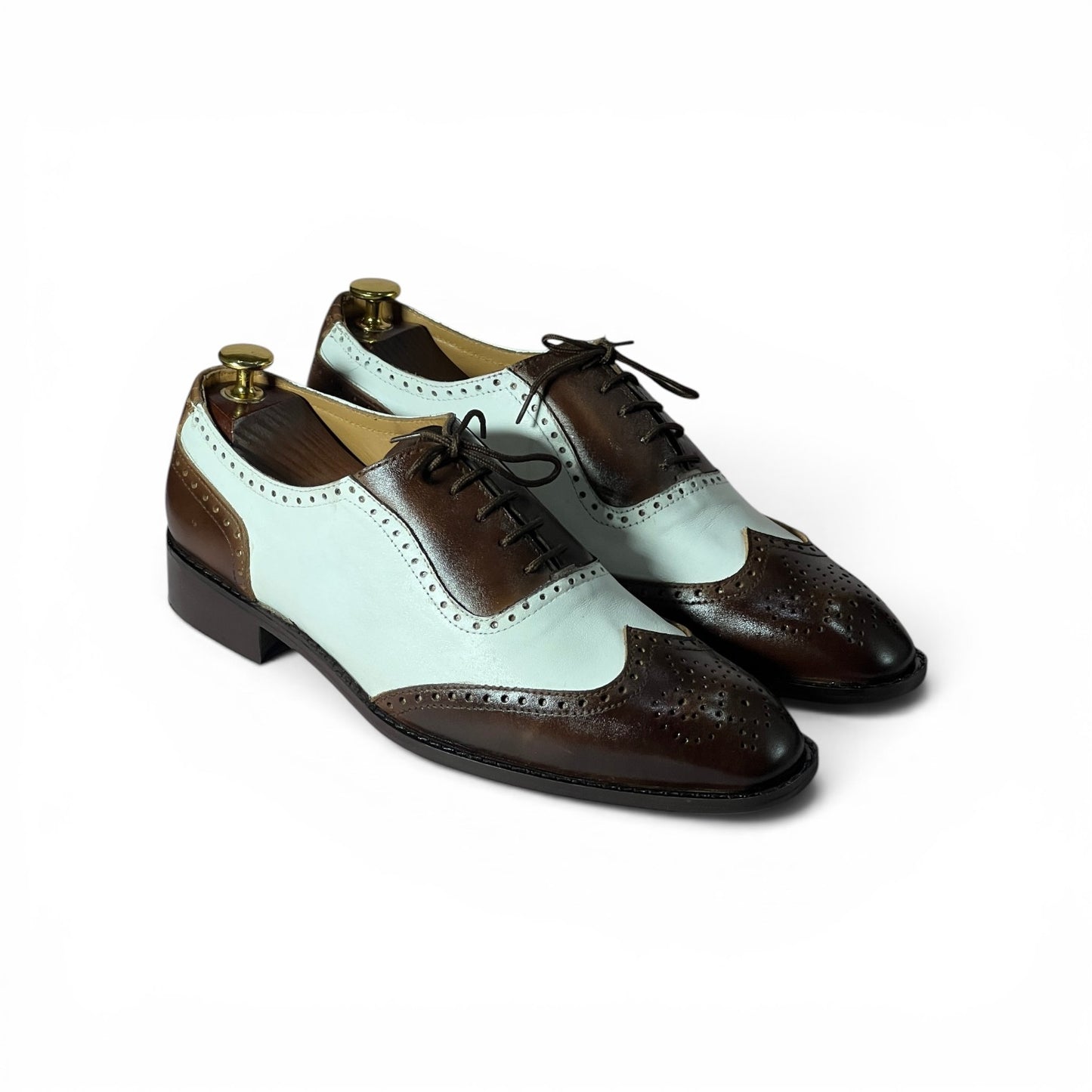 A pair of men's wingtip oxford shoes with a color-blocked design featuring dark brown leather and a pale mint green leather, displayed on white background with shoe trees inside..