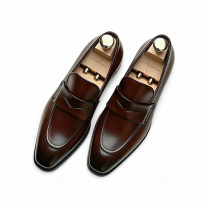 Pair of brown loafers with gold accents on a white background
