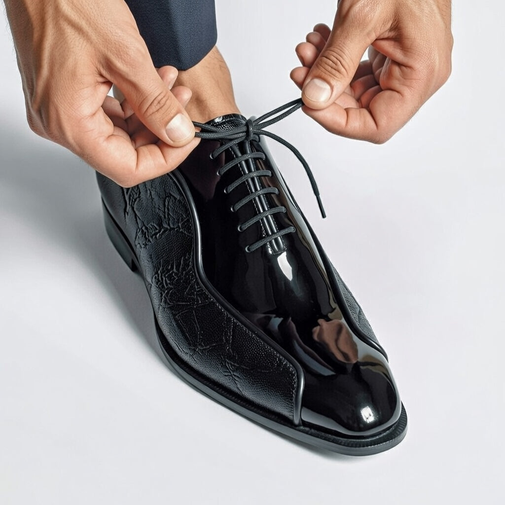 Person tying the laces of a black dress shoe on a light gray background