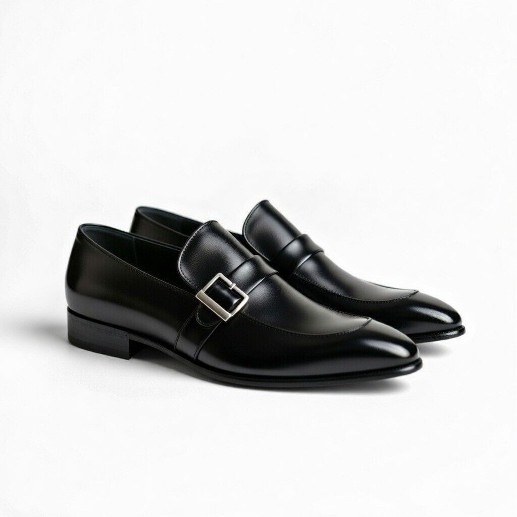 Pair of black dress shoes with a silver buckle on a white background