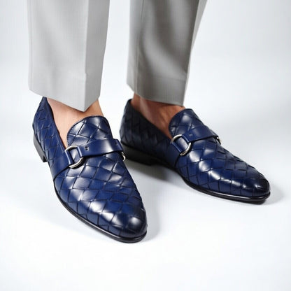 Blue textured dress shoes with buckles worn with light gray pants on a white background