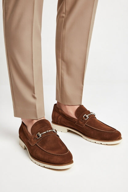 Brown loafers worn with beige pants on a white background