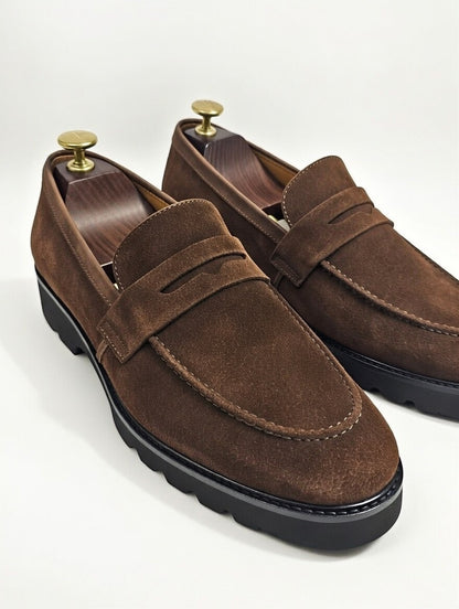 Brown suede loafers with gold accents on a white background