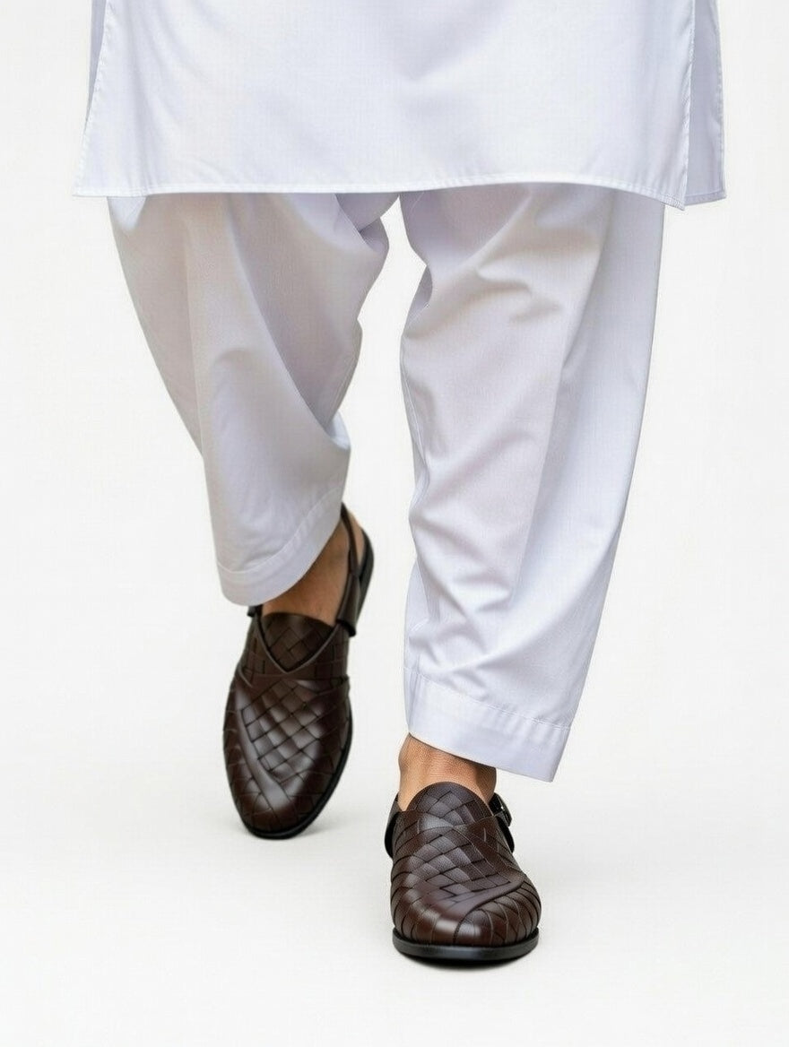 Brown loafers worn with white pants on a white background
