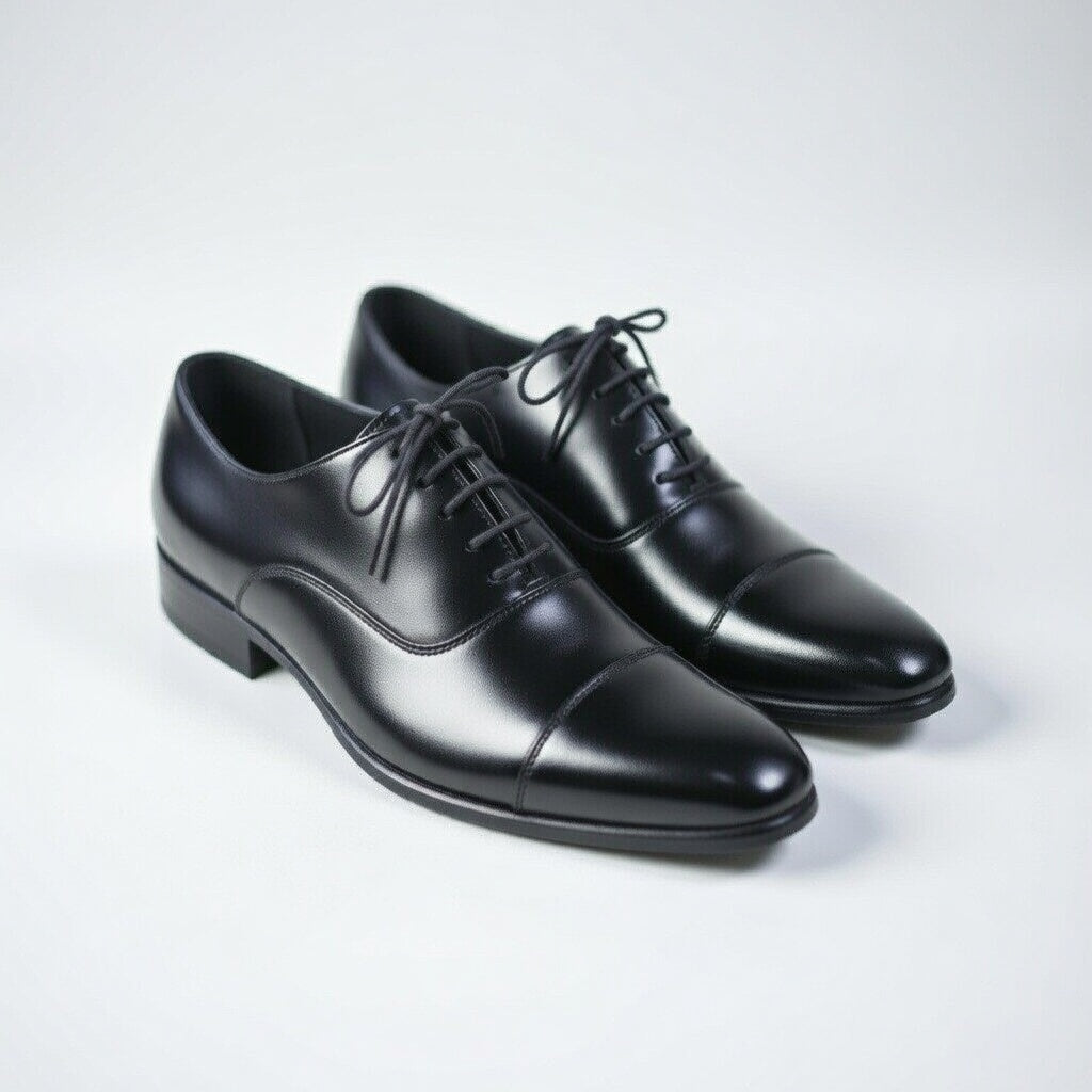 Pair of black leather dress shoes on a light gray background