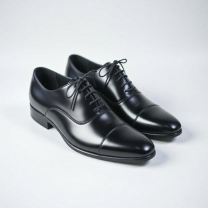 Pair of black leather dress shoes on a light gray background