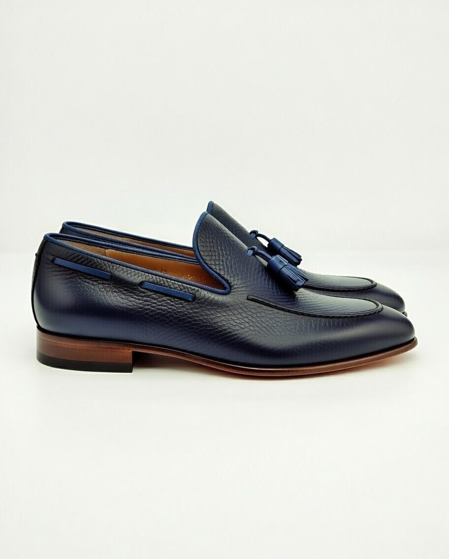 Pair of navy blue loafers with brown soles on a white background