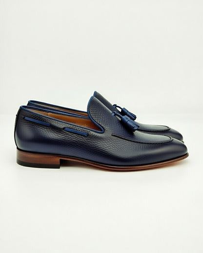 Pair of navy blue loafers with brown soles on a white background