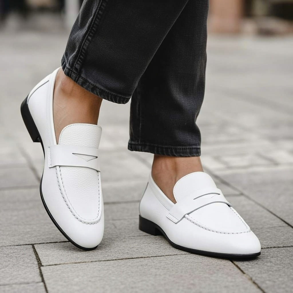 White loafers worn with black pants on a pavement background