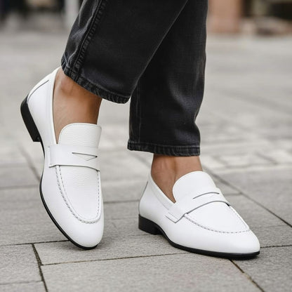 White loafers worn with black pants on a pavement background
