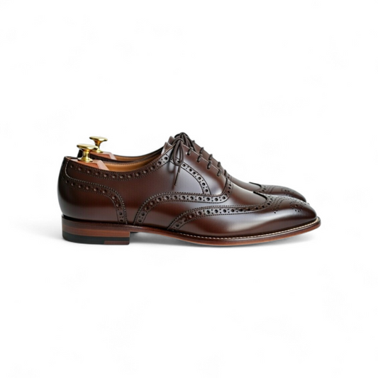 Brown leather dress shoes with brogue detailing on a white background