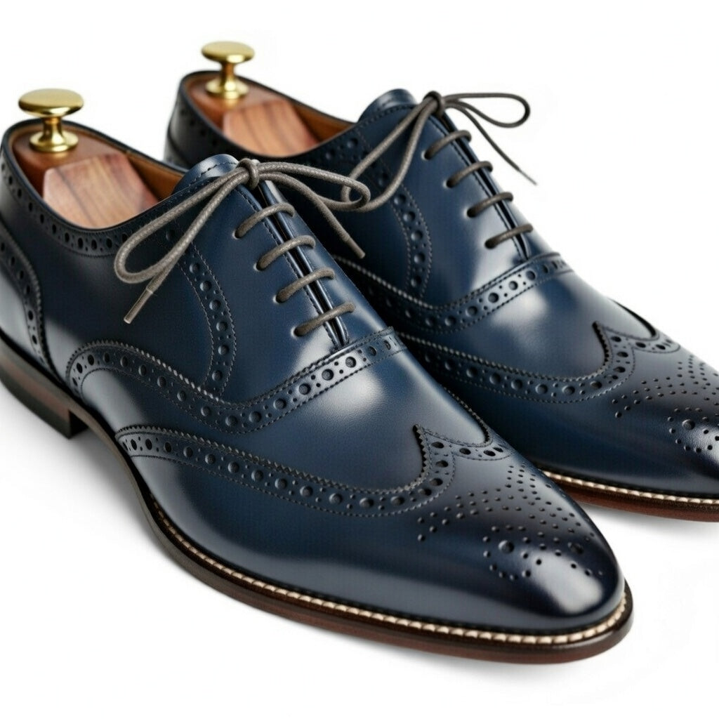Pair of navy blue leather dress shoes with wingtip design on a white background