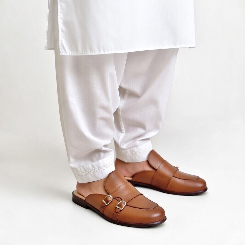 Brown loafers worn with white pants on a light background