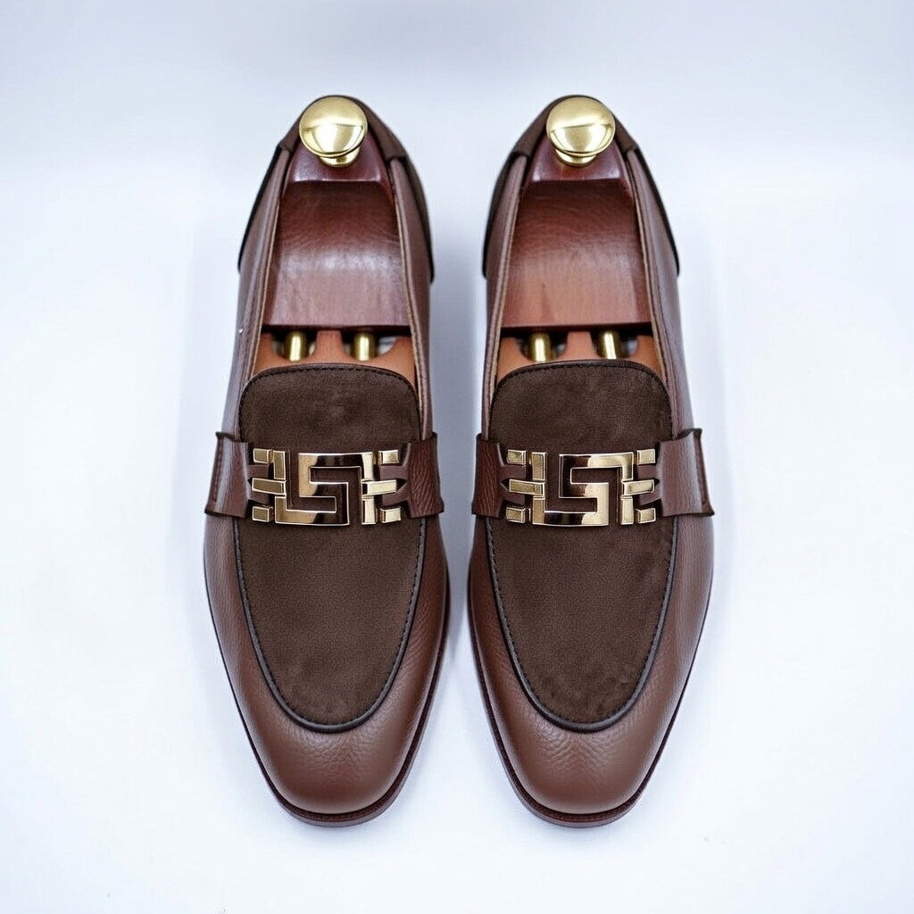 Brown loafers with gold accents on a white background
