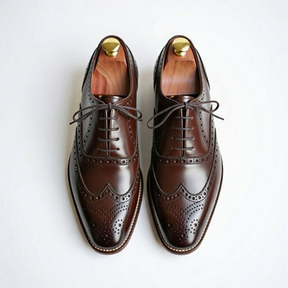 Pair of brown leather dress shoes with wooden insoles on a white background
