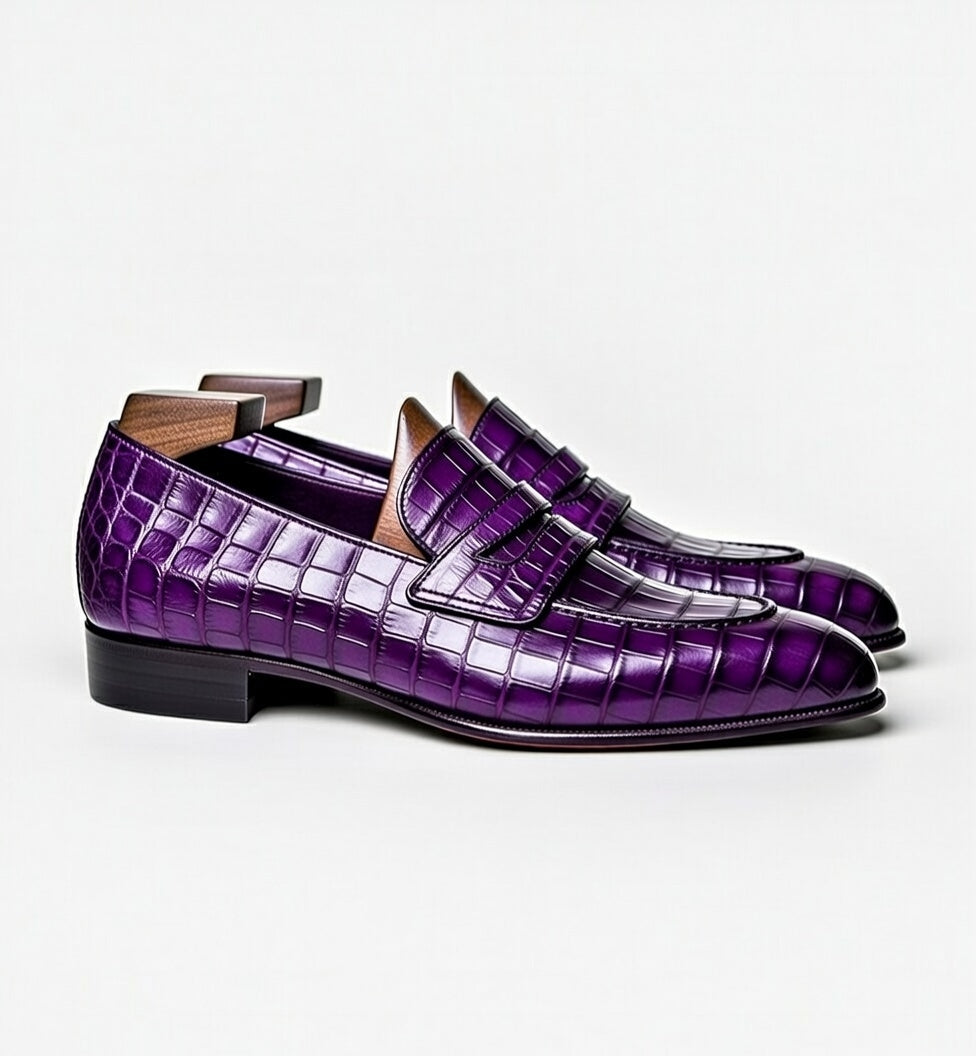 Pair of purple crocodile-patterned loafers on a white background