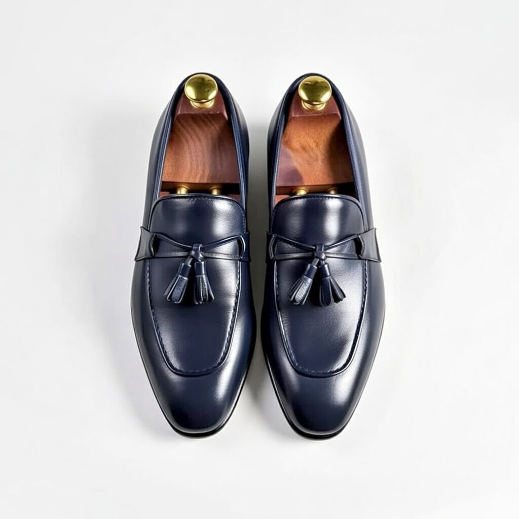 Pair of navy loafers with gold buttons on a white background