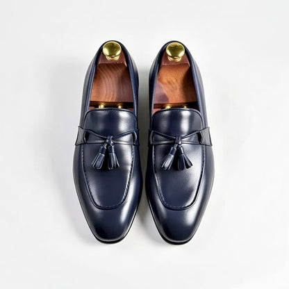 Pair of navy loafers with gold buttons on a white background