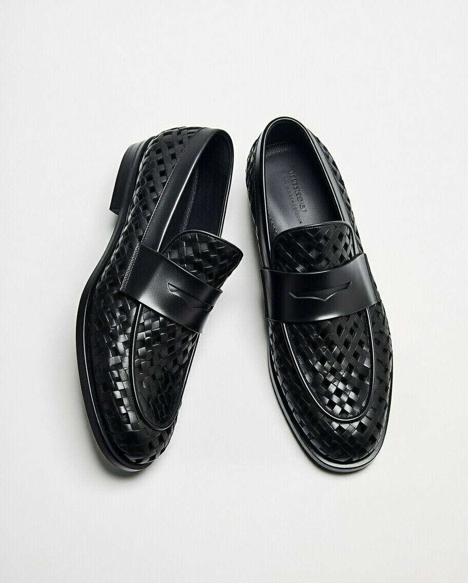 Black perforated loafers on a light gray background
