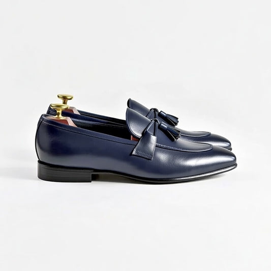 Pair of blue leather loafers with a bow on a light gray background