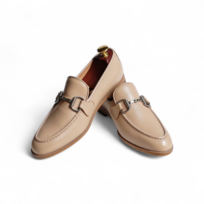 Pair of beige loafers with metal buckles on a white background
