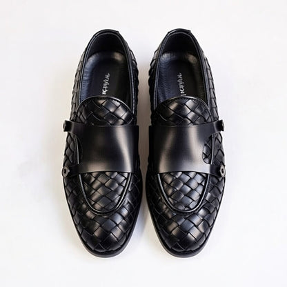 Pair of black leather loafers with woven pattern on a white background