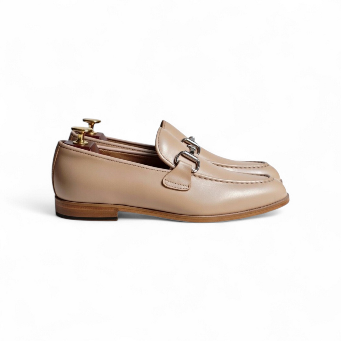 Pair of beige loafers with a gold buckle on a white background