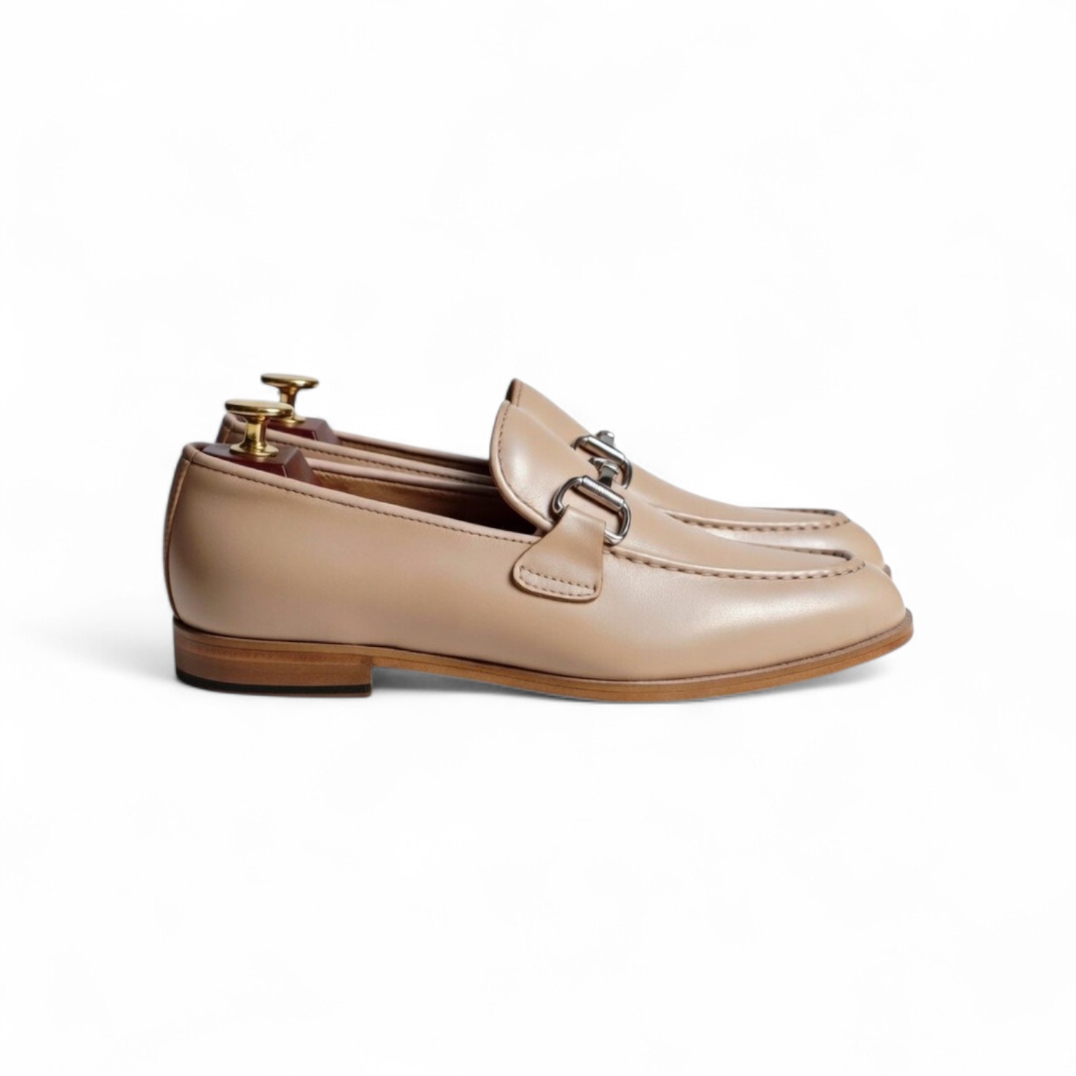 Pair of beige loafers with a gold buckle on a white background