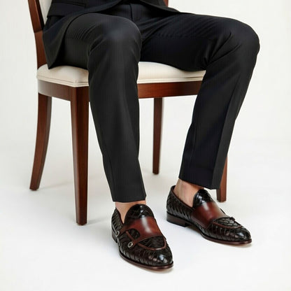Person wearing black suit pants and brown loafers sitting on a chair.