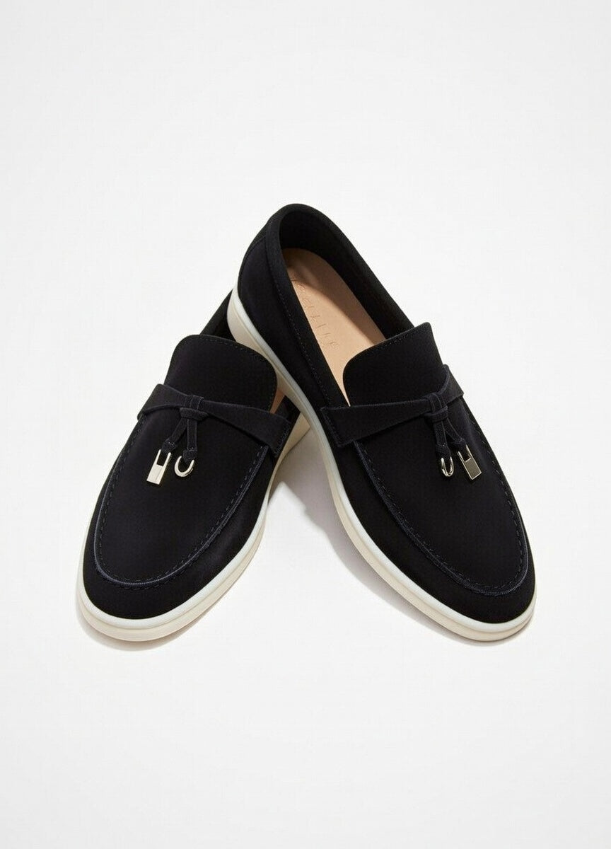 Pair of black loafers with tassels on a white background