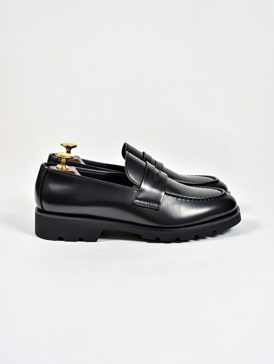 Black leather loafers on a light gray background
