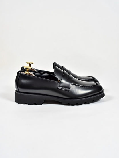 Black leather loafers on a light gray background