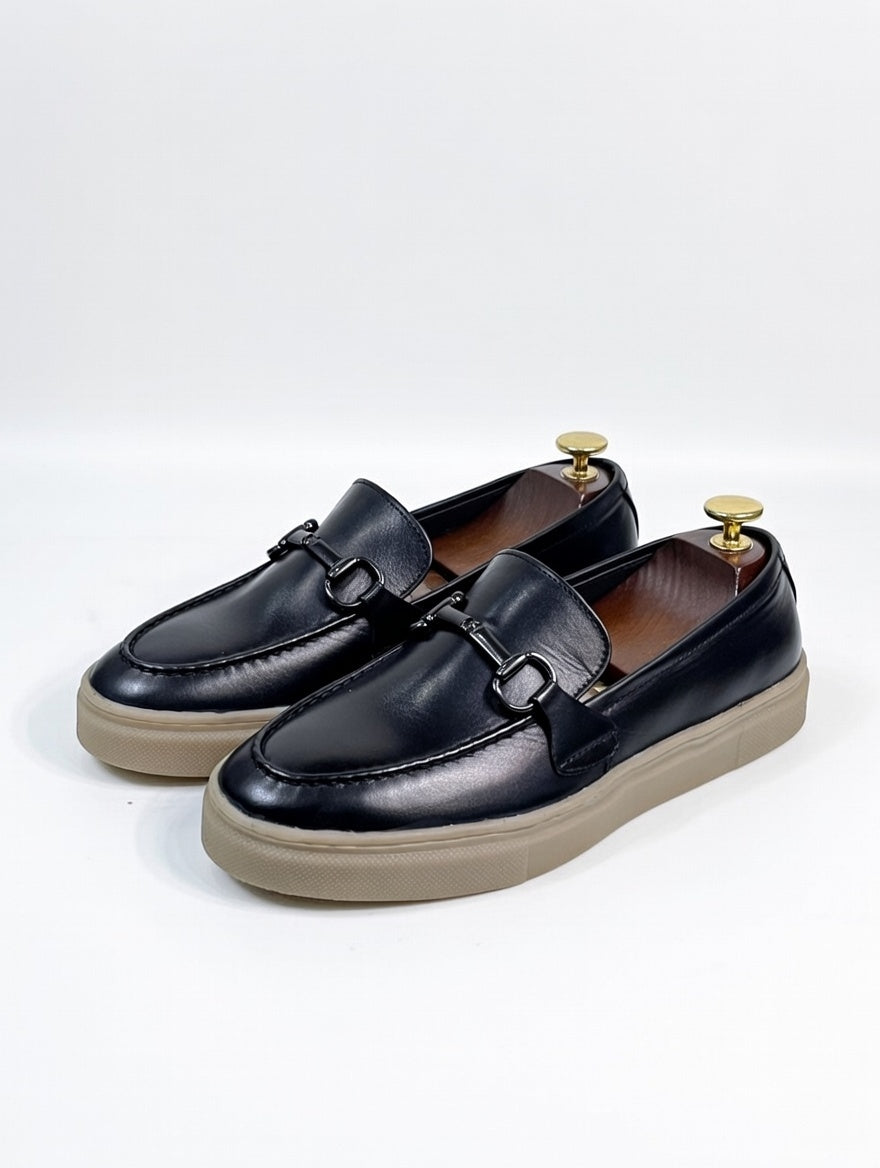 Black loafers with beige soles on a white background
