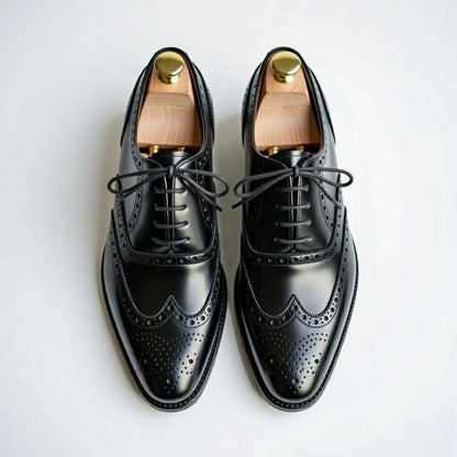 Pair of black leather dress shoes with wooden soles on a white background