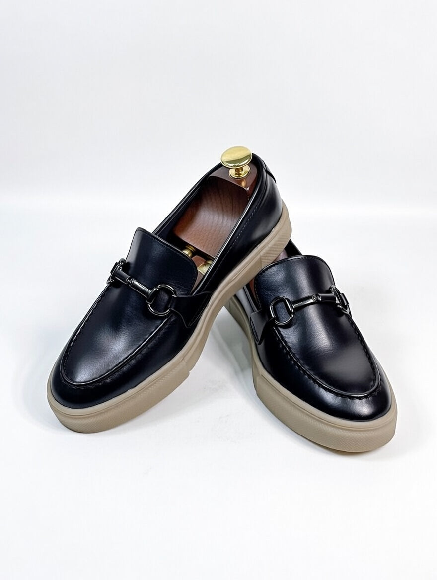 Black loafers with tan soles on a white background