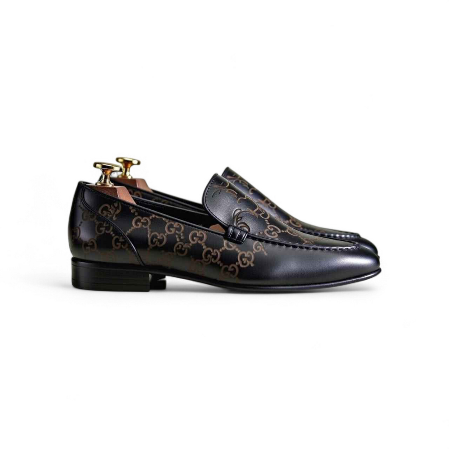 Black loafers with gold accents on a white background